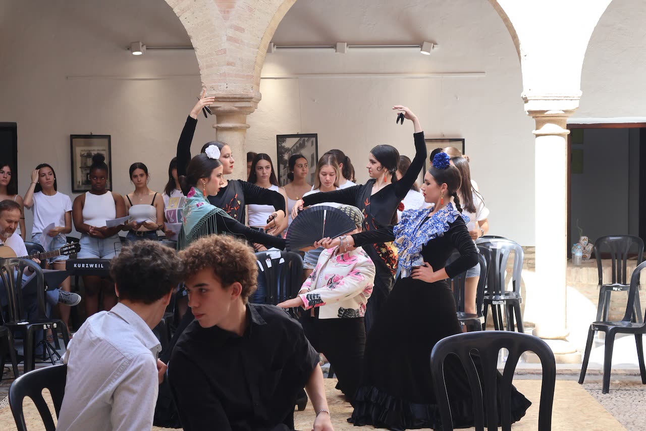 Conjunto de estudiantes bailando y cantando en el patio del palacio