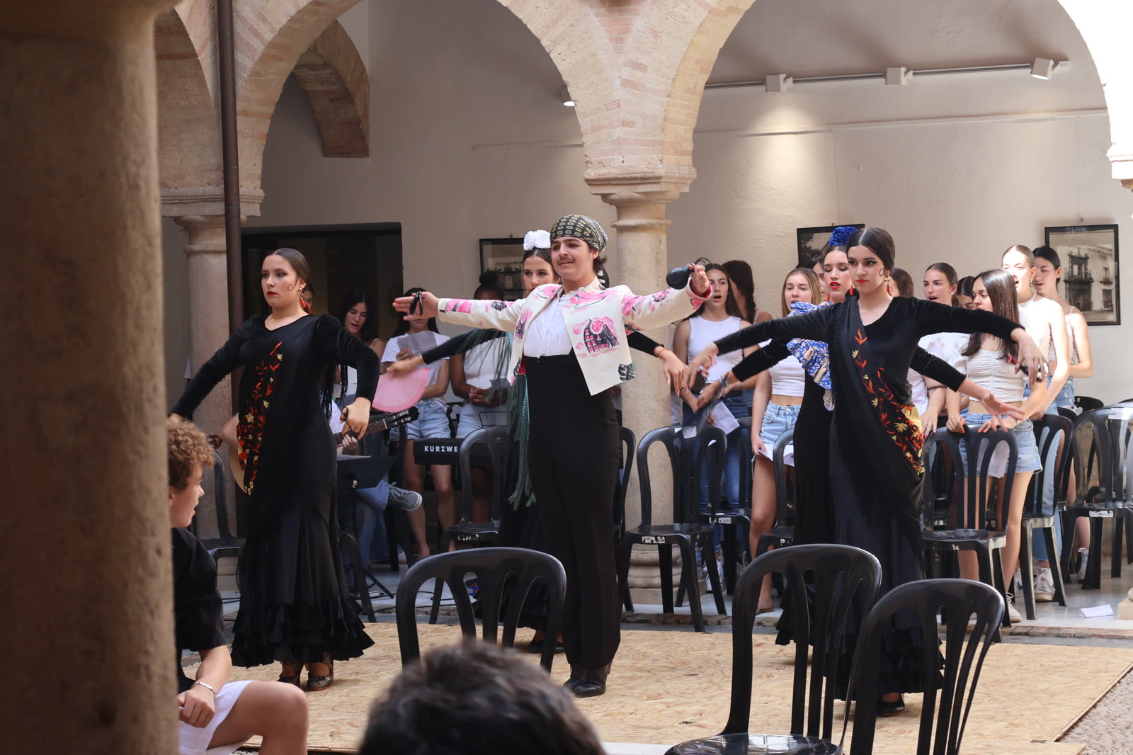 Bailaoras y bailaores organizan una figura coreográfica con el coro al fondo