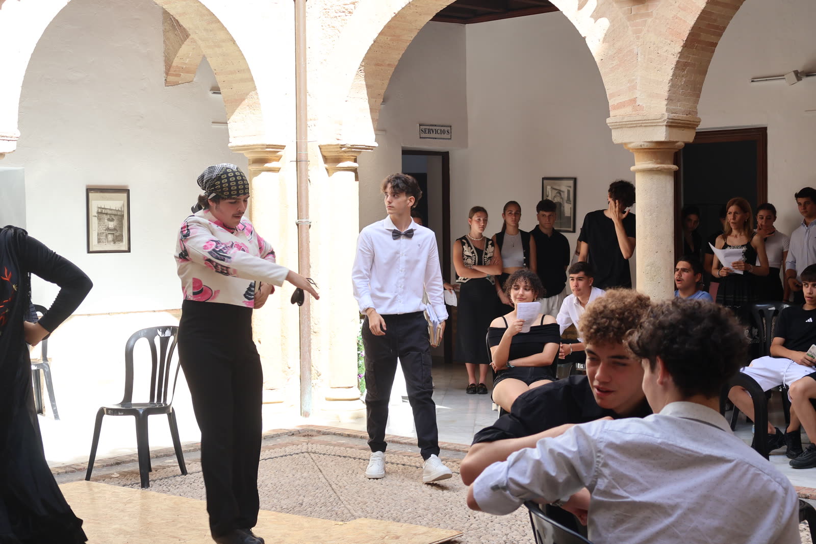 Intérpretes avanzan por el patio durante una escena de transición