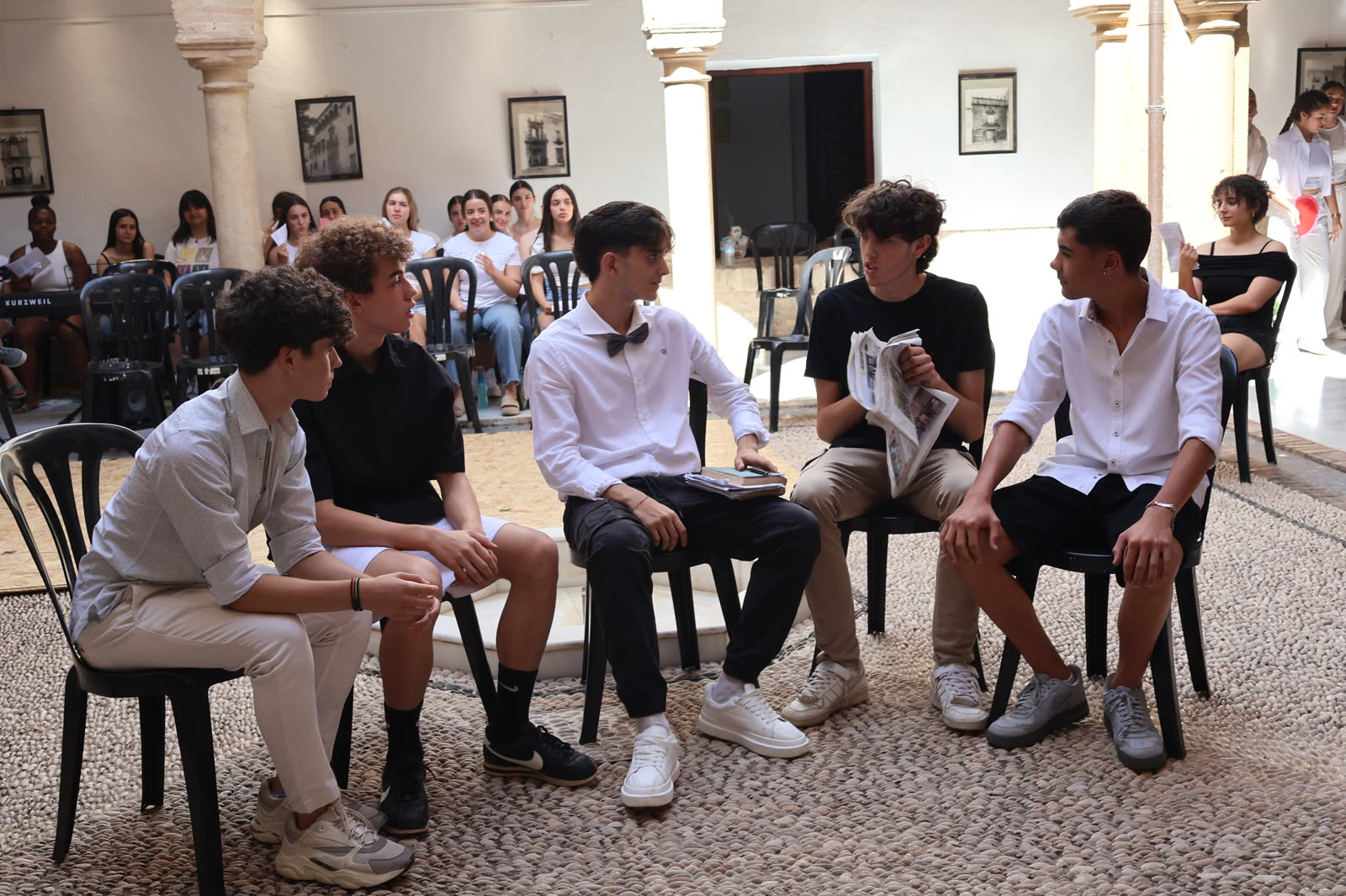 Estudiantes dialogan en escena con un periódico como elemento dramático