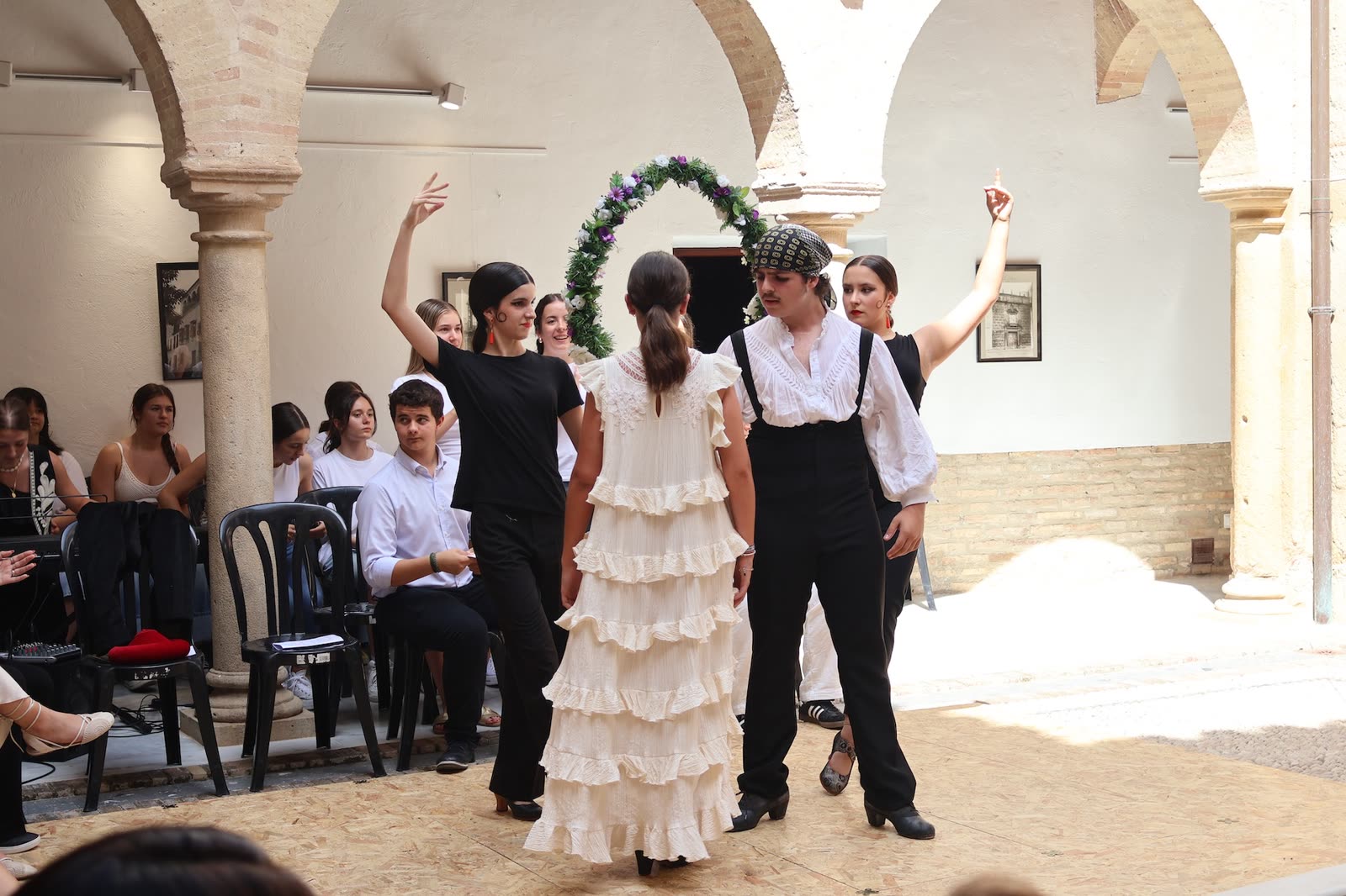 Tres bailarinas ejecutan una coreografía con músicos y coro en segundo plano